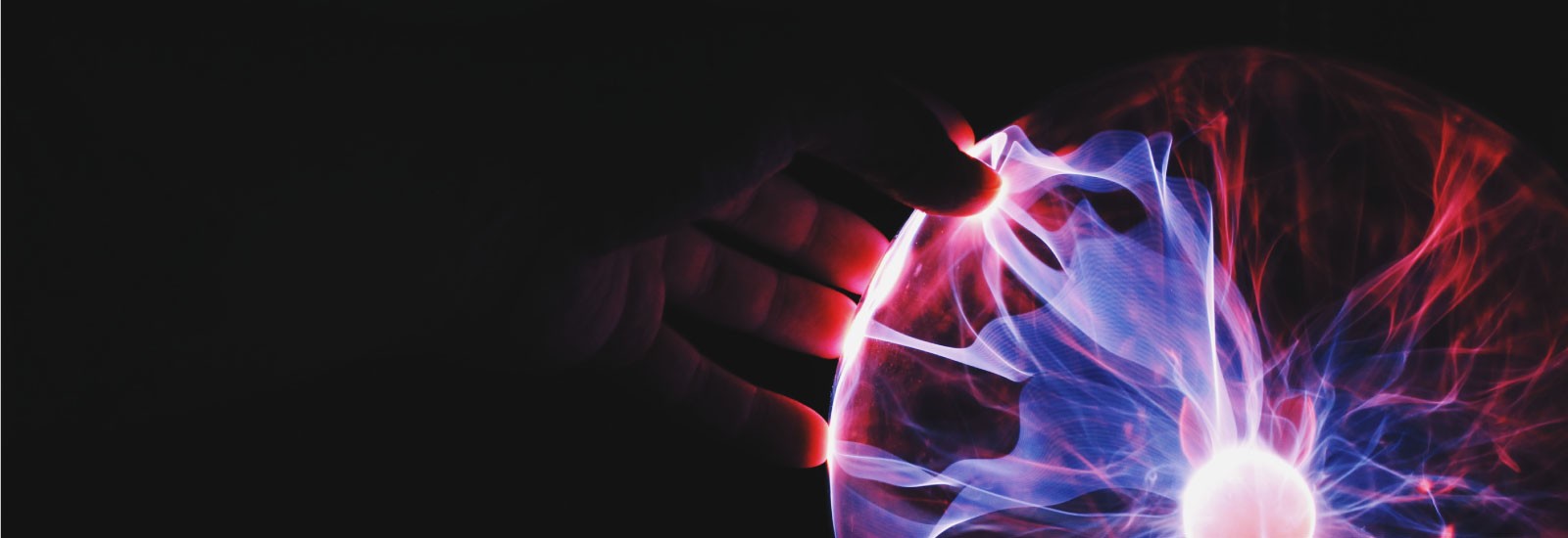 A hand is reaching out to a glass plasma ball.