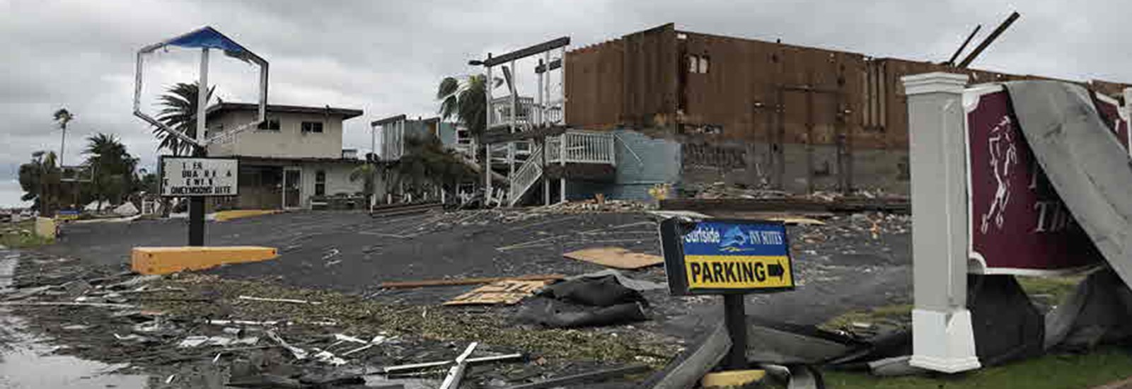 storm debris and a damaged building under a cloudy sky in Rockport, TX, following Hurricane Harvey in 2017