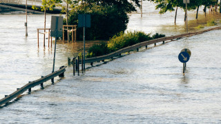 Flooded streets showing road signs and trees underwater.