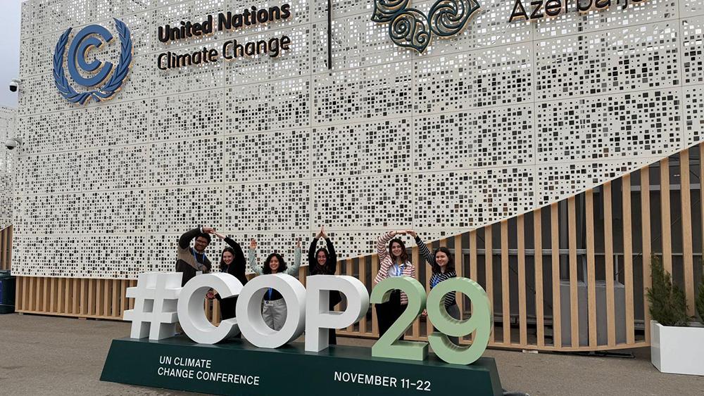 Students pose at COP 29 statue