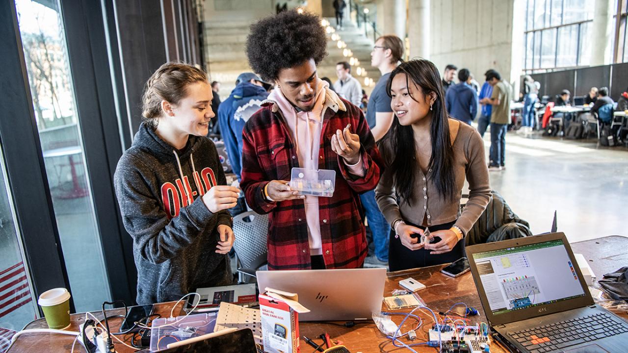 Three students work on electronics